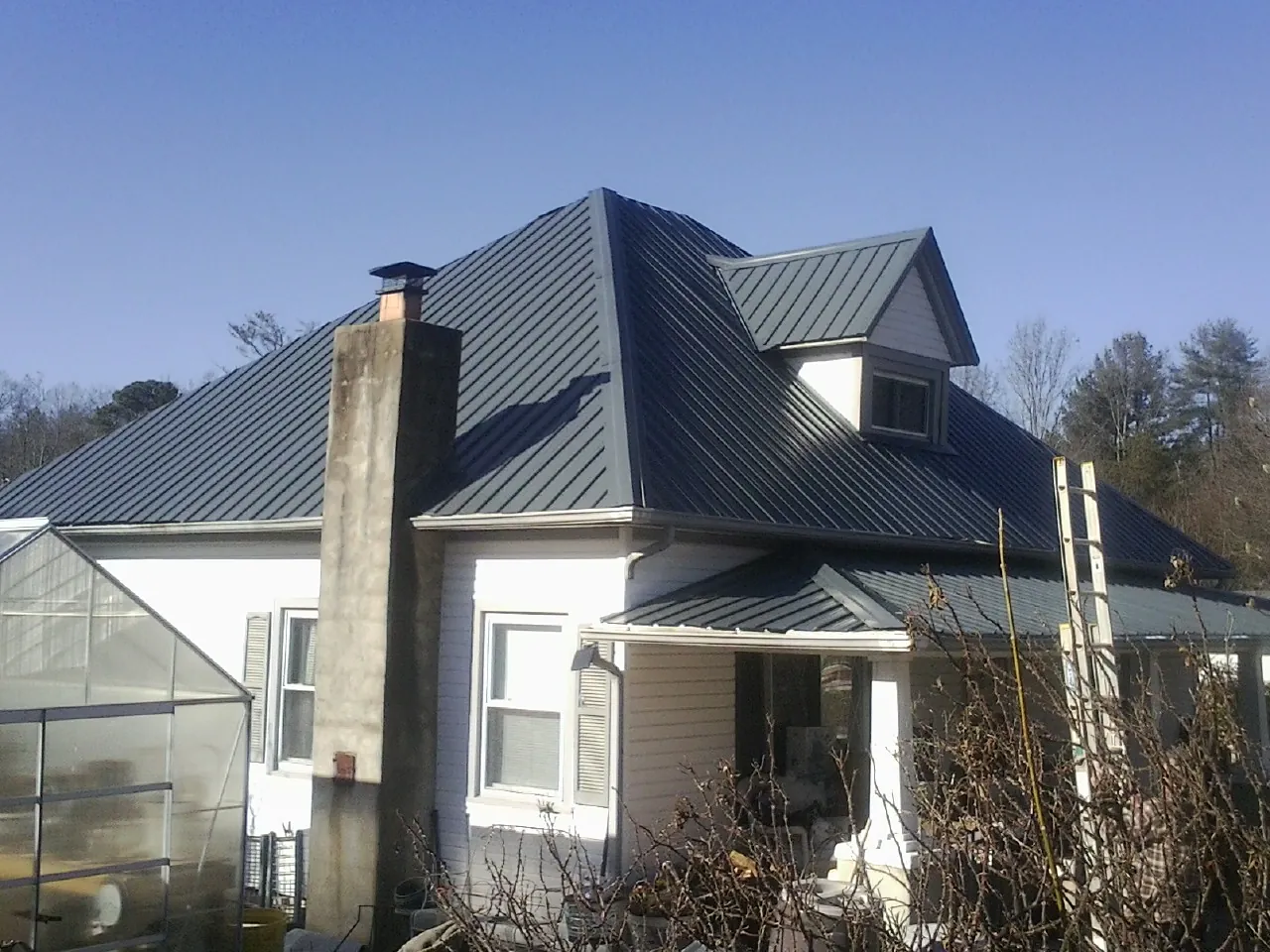Dark blue standing seam metal roof on a white farmhouse with dormer — Slate & Tile Roof Repair by Roofing Brothers in Whitmore