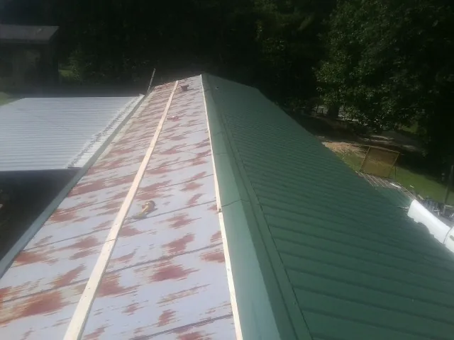 Old rusted panels beside newly installed green metal roofing — Wind Damage Roof Repair by Roofing Brothers in Whitmore