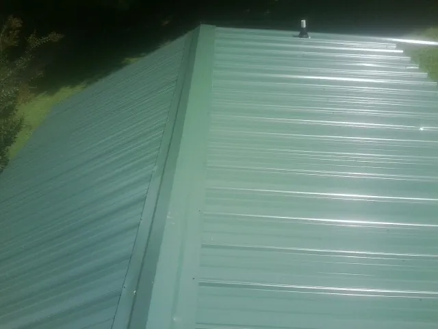 New green metal panels meeting at the ridge of a roof — Flat Roof Repair work by our crew in Whitmore