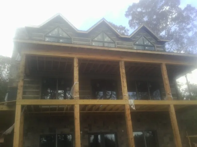 Dormers and porch framing on a large log home under construction — Roof Coating work by our crew in Whitmore