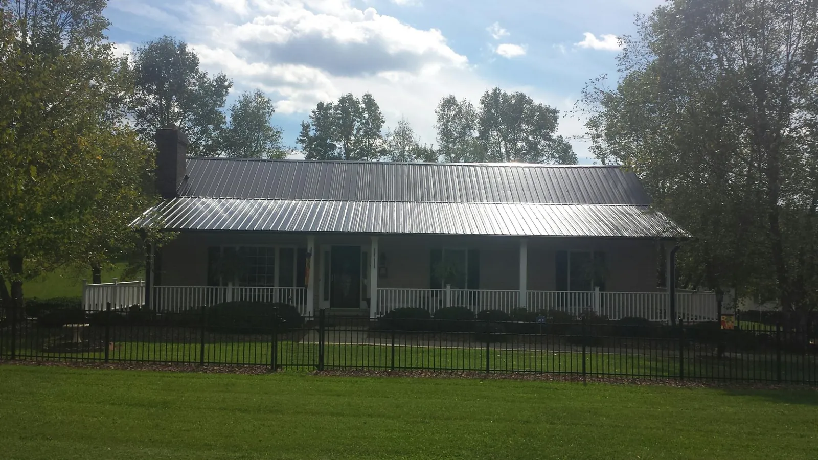 Gray metal roof on a brick ranch with a full width front porch — Gutter Guard Installation work by our crew in Whitmore