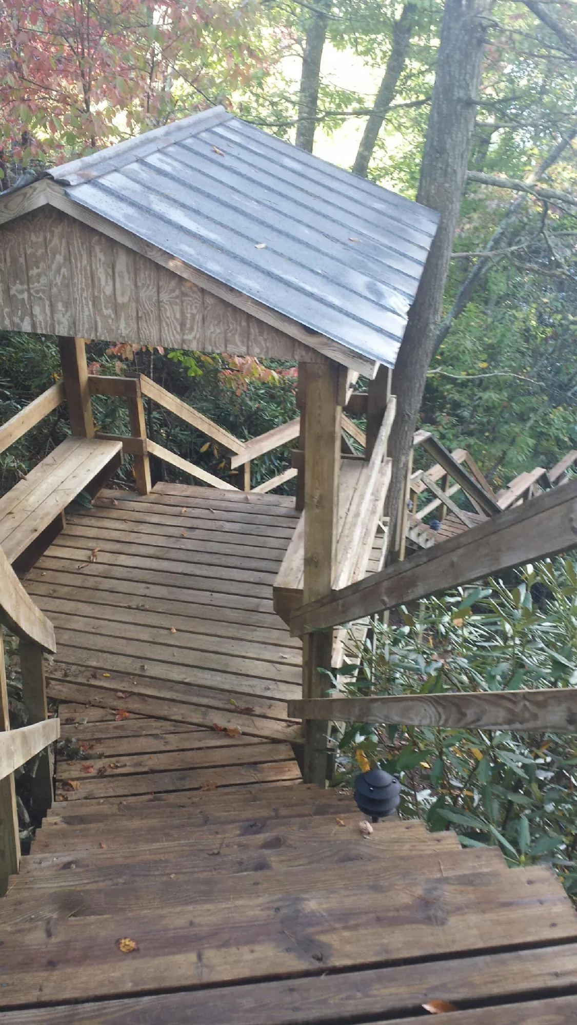 Metal roofed shelter over wooden steps on a wooded walkway — Skylight Repair & Installation work by our crew in Whitmore