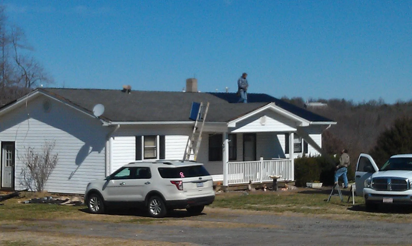 Roofers stripping shingles from a white ranch house roof in Whitmore